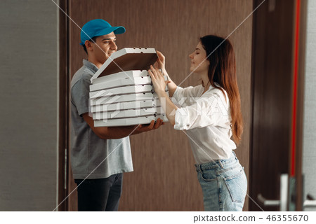 Delivery boy shows pizza to female customer Delivery boy shows pizza to female customer 46355670