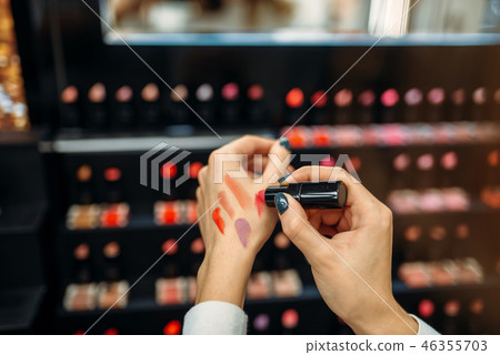 Female customer testing lipstick in make-up shop Female customer testing lipstick in make-up shop 46355703