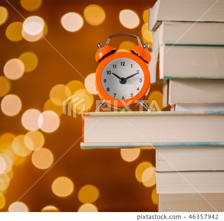 Vintage alarm clock and pile of books Vintage alarm clock and pile of books 46357942