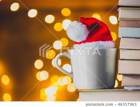 White cup and Christmas hat near books 46357963