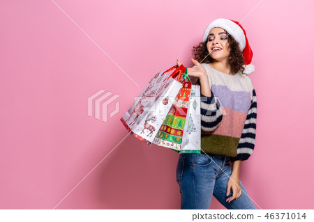 Beautiful women wearing bright Christmas carrying colorful shopping bags. On pink background 46371014