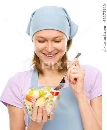 Young attractive woman is eating salad using fork Young attractive woman is eating salad using fork 46375140