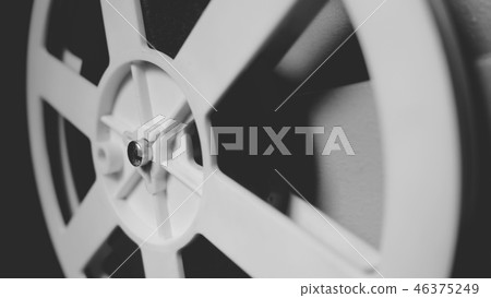 Close-up of spinning reel. Old 8mm film projector showing film at night in dark room. Vintage retro 46375249