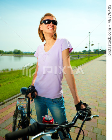 Young woman is standing behind bicycle Young woman is standing behind bicycle 46376405