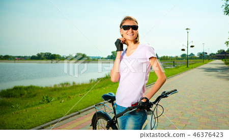 Young woman is standing behind bicycle 46376423