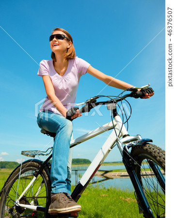 Young woman is sitting on her bicycle Young woman is sitting on her bicycle 46376507