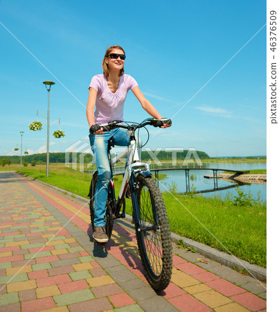 Young woman is riding on her bicycle Young woman is riding on her bicycle 46376509