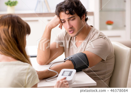 Wife checking husband's blood pressure Wife checking husband's blood pressure 46378084