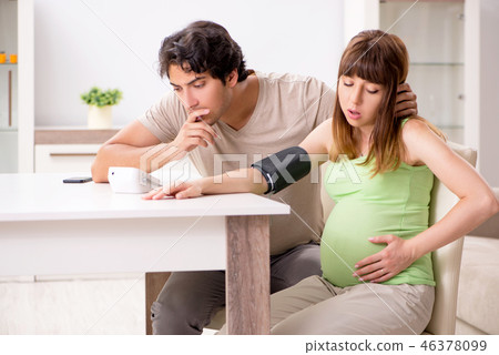 Husband checking pregnant wife's blood pressure Husband checking pregnant wife's blood pressure 46378099