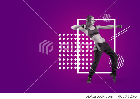 A young attractive female dancer in sleeveless crop top and sweatpants dancing on a purple A young attractive female dancer in sleeveless crop top and sweatpants dancing on a purple 46379250