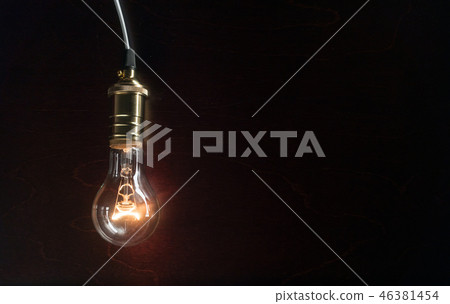 The light bulb illuminates on wooden background 46381454