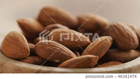 Closeup of organic almonds in wood bowl on wooden table Closeup of organic almonds in wood bowl on wooden table 46381474