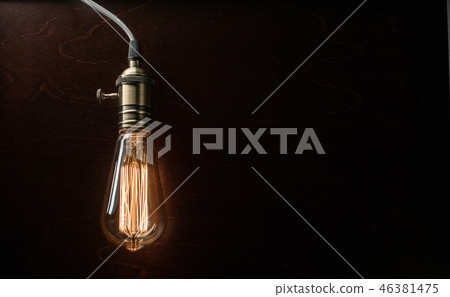 The light bulb illuminates on wooden background The light bulb illuminates on wooden background 46381475