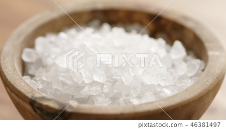 Closeup of coarse sea salt in wooden bowl on table Closeup of coarse sea salt in wooden bowl on table 46381497