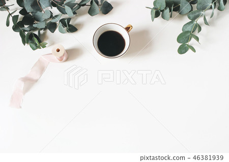 Floral composition made of green eucalyptus leaves and branches on white wooden background with cup 46381939