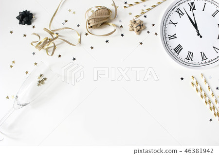 New Year still life composition with golden confetti stars, wine glass, drinking straws and clock 46381942