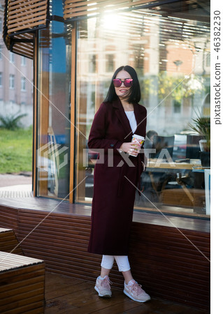 Cheerful gorgeous brunette in winter fashion holding disposable cup on urban background 46382230