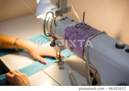 Girl seamstress in the light of a desk lamp stitch 46382652