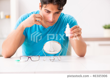 Man trying contact lenses at home Man trying contact lenses at home 46385906