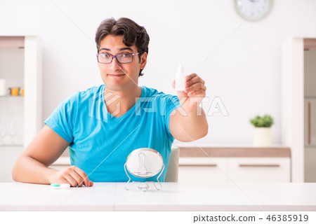 Man trying contact lenses at home 46385919