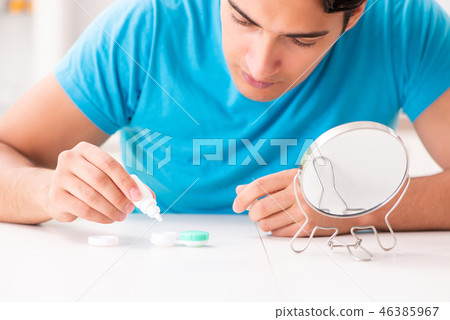 Man trying contact lenses at home 46385967
