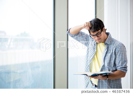 Young handsome student standing at the window Young handsome student standing at the window 46387436