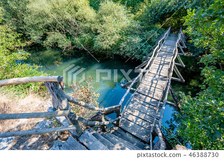 Small wooden hand-made bridge over narrow river Small wooden hand-made bridge over narrow river 46388730