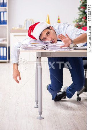 Young handsome employee celebrating Christmas at workplace  46388782