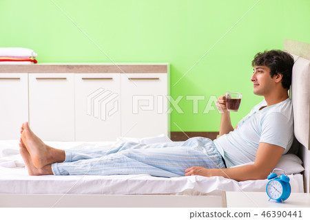 Young handsome man drinking coffee in the bed Young handsome man drinking coffee in the bed 46390441