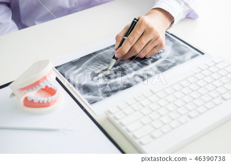Concentrated dentist sitting at table with jaw samples tooth mod 46390738