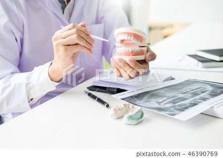 Concentrated dentist sitting at table with jaw samples tooth mod 46390769