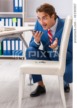 Office prank with sharp thumbtacks on chair 46390997