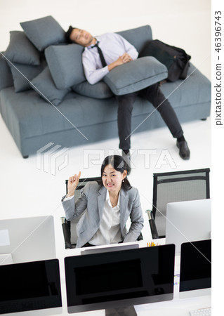Woman working, man napping at work. Woman working, man napping at work. 46396743