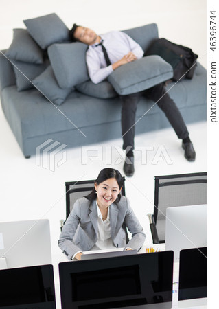 Woman working, man napping at work. Woman working, man napping at work. 46396744