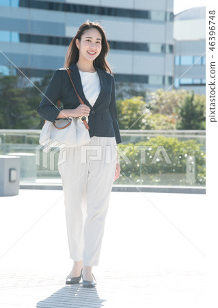 年輕日本婦女佩帶的女商人衣服在辦公區 年輕日本婦女佩帶的女商人衣服在辦公區 46396748