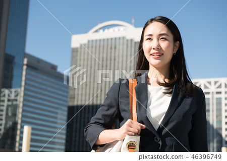 年輕日本婦女佩帶的女商人衣服在辦公區 年輕日本婦女佩帶的女商人衣服在辦公區 46396749