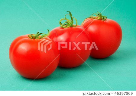 Three red tomatoes on a green background 46397869