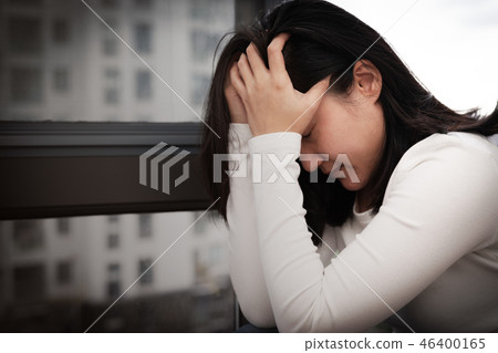 depressed women sitting near window alone sadness 46400165