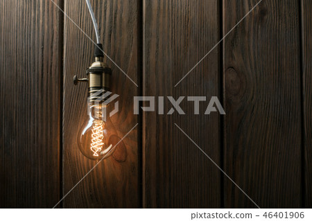 The light bulb illuminates on wooden background 46401906