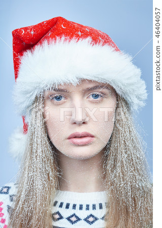 Frozen girl with snow on face wearing Santa hat Frozen girl with snow on face wearing Santa hat 46404057