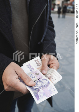 man offering some czech koruna banknotes. 46405133
