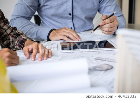 Construction engineering or architect discuss a blueprint while 46412332