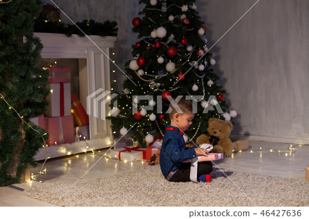 little boy opens gifts at Christmas New Year holiday lights little boy opens gifts at Christmas New Year holiday lights 46427636