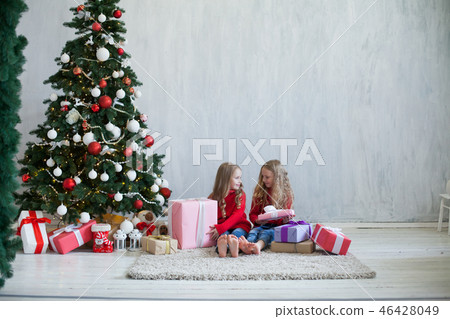 two little girls opens Christmas gifts at the Christmas tree new year holiday house two little girls opens Christmas gifts at the Christmas tree new year holiday house 46428049