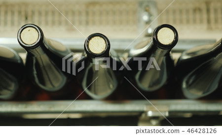 Wine bottles closed with a cork stopper move along the conveyor belt. Wine bottles closed with a cork stopper move along the conveyor belt. 46428126