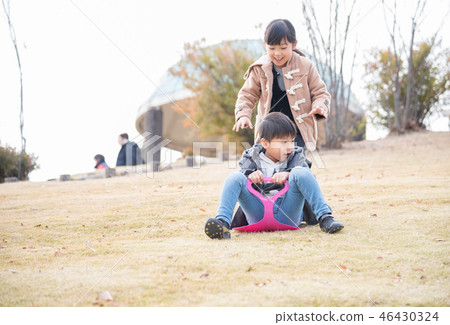Child sliding on grass in winter park 46430324