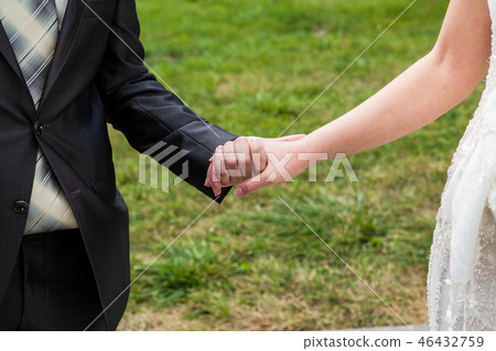 The groom holds the bride by the hand The groom holds the bride by the hand 46432759