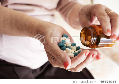 senior woman with a pile of pills in his hand senior woman with a pile of pills in his hand 46434044