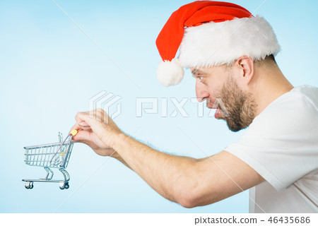 Man in santa hat holds empty shopping cart Man in santa hat holds empty shopping cart 46435686