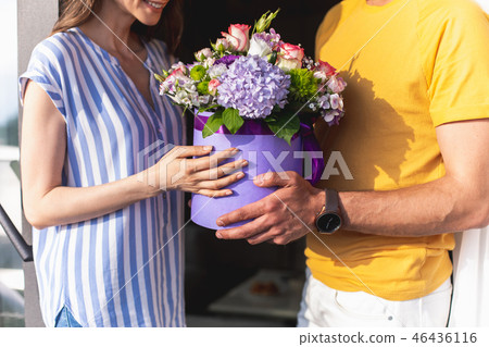 Cheerful lady taking bouquet from young man Cheerful lady taking bouquet from young man 46436116